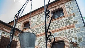 Un bâtiment en pierre avec un seau en métal suspendu à une chaîne.