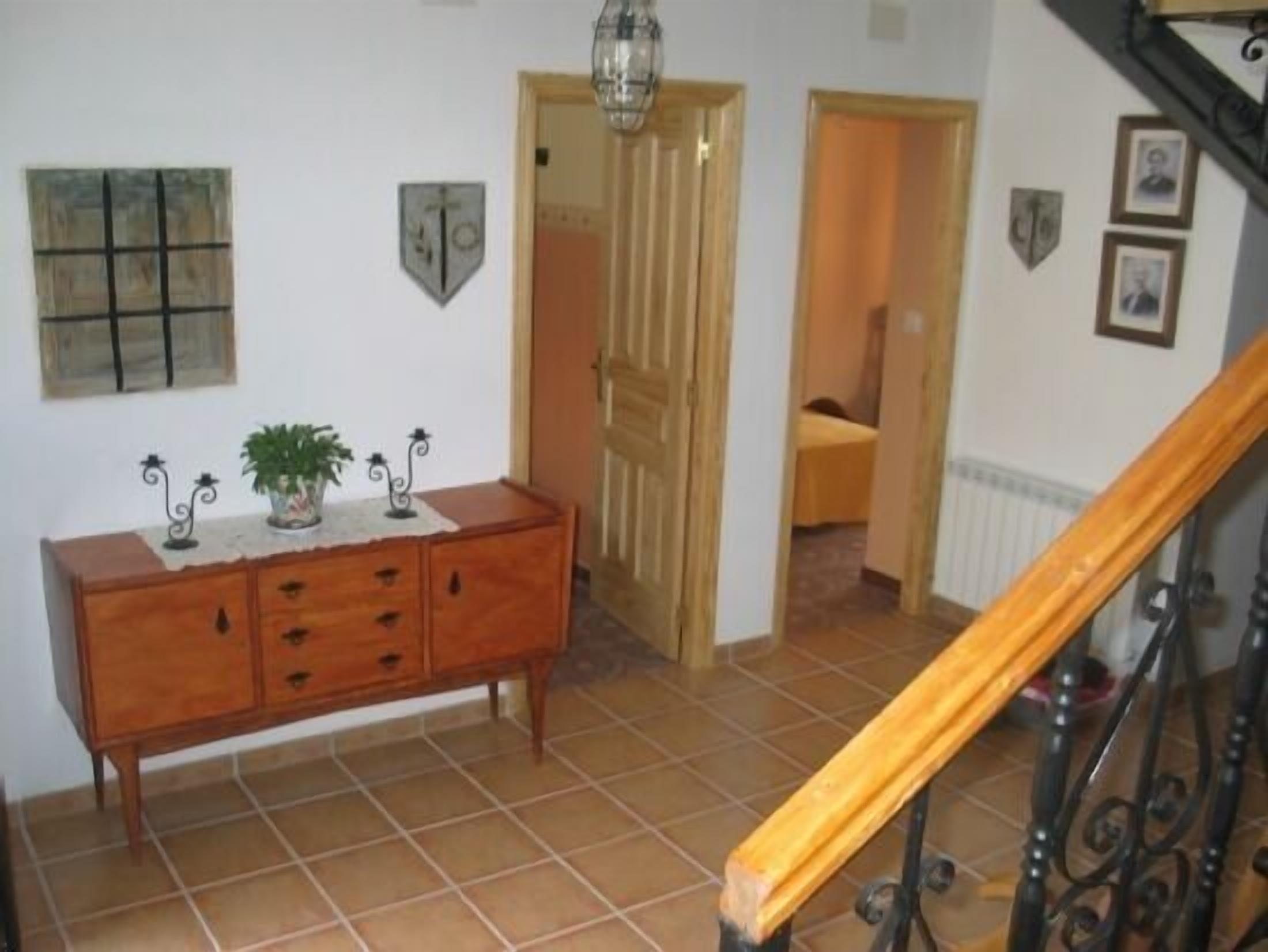 Un couloir avec un banc en bois, un sol carrelé et un escalier doté d’une rampe en bois.