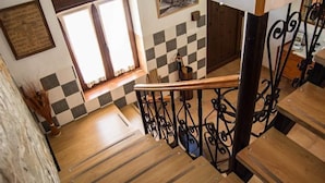 Un escalier en bois avec des rampes en métal noir, un motif à carreaux sur le mur et une fenêtre avec des rideaux.