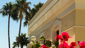 A building with a balcony, palm trees, and red flowers. - Directly on the Golf course.Huge Golf and Spa Mansion 8 min from Puerto Banus (Benahavís)