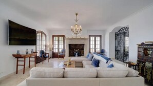 A spacious living room with a large sofa, a fireplace, and a chandelier. - Directly on the Golf course.Huge Golf and Spa Mansion 8 min from Puerto Banus (Benahavís)