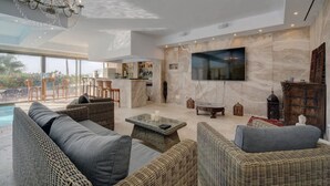 A spacious living area with a large TV, wicker furniture, a bar area, and a pool view. - Directly on the Golf course.Huge Golf and Spa Mansion 8 min from Puerto Banus (Benahavís)