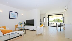 Een moderne woonkamer met een televisie, bank en eethoek.