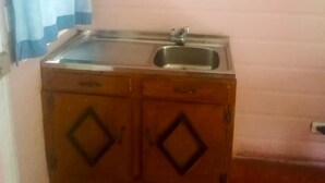 A small kitchen with a sink, wooden cabinets, and a blue curtain. - Cabañas Las Orquideas (Miramar)