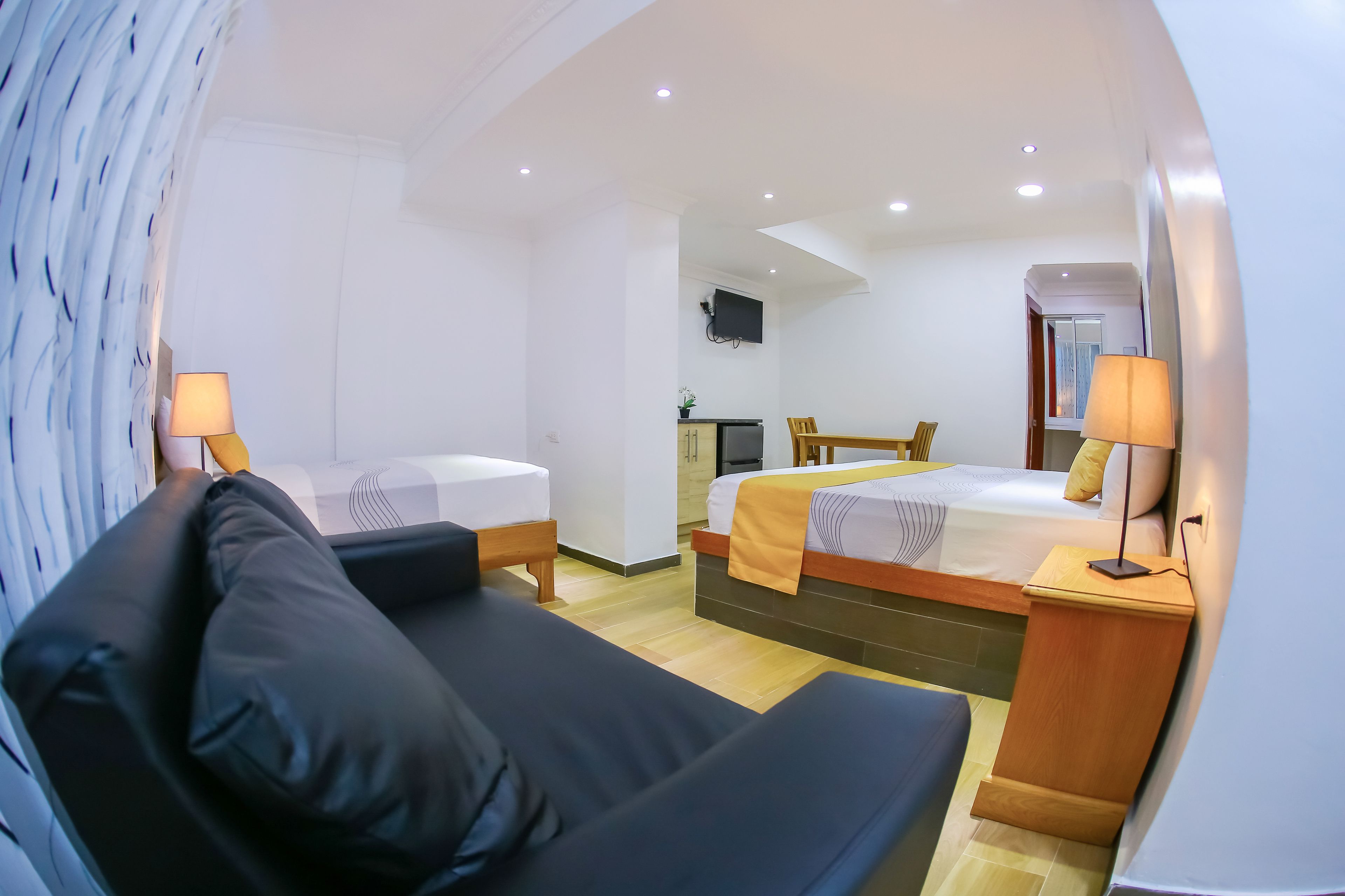 Una habitación de hotel moderna con dos camas individuales, un sofá, un escritorio y una televisión.