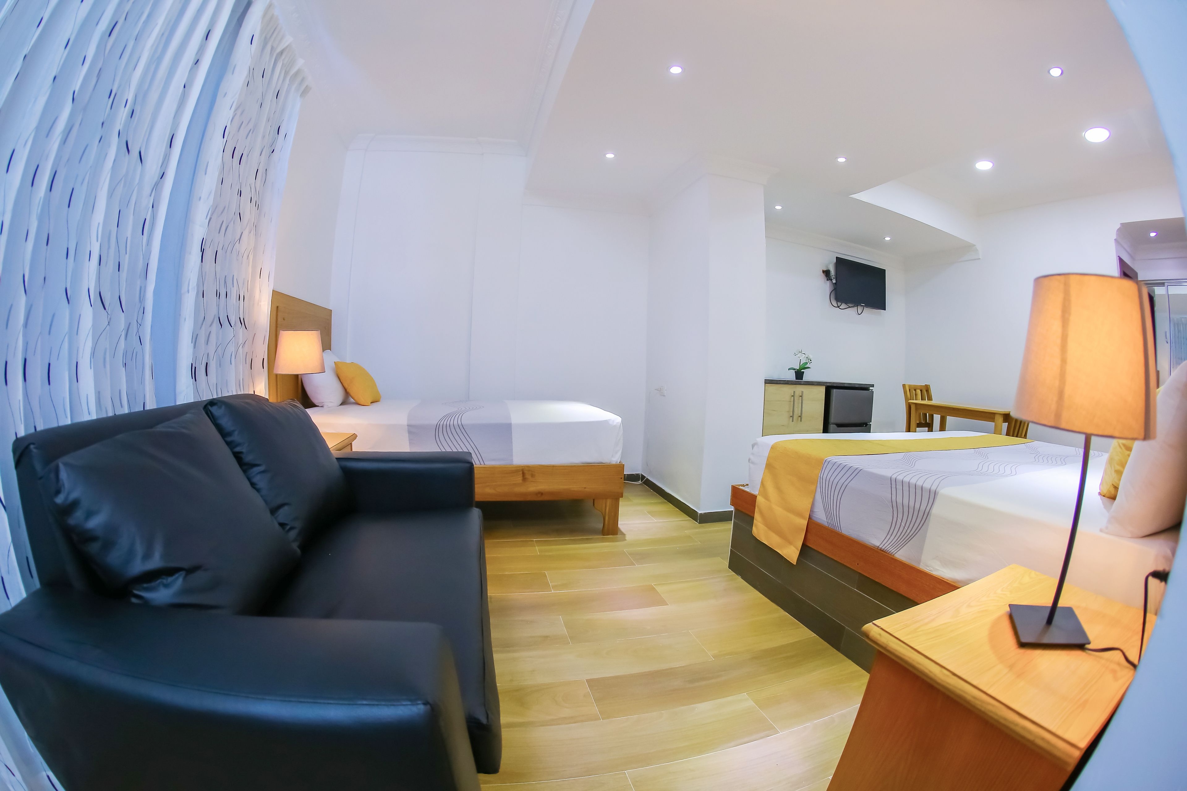 Una habitación de hotel moderna con sofá, cama, escritorio y televisor.