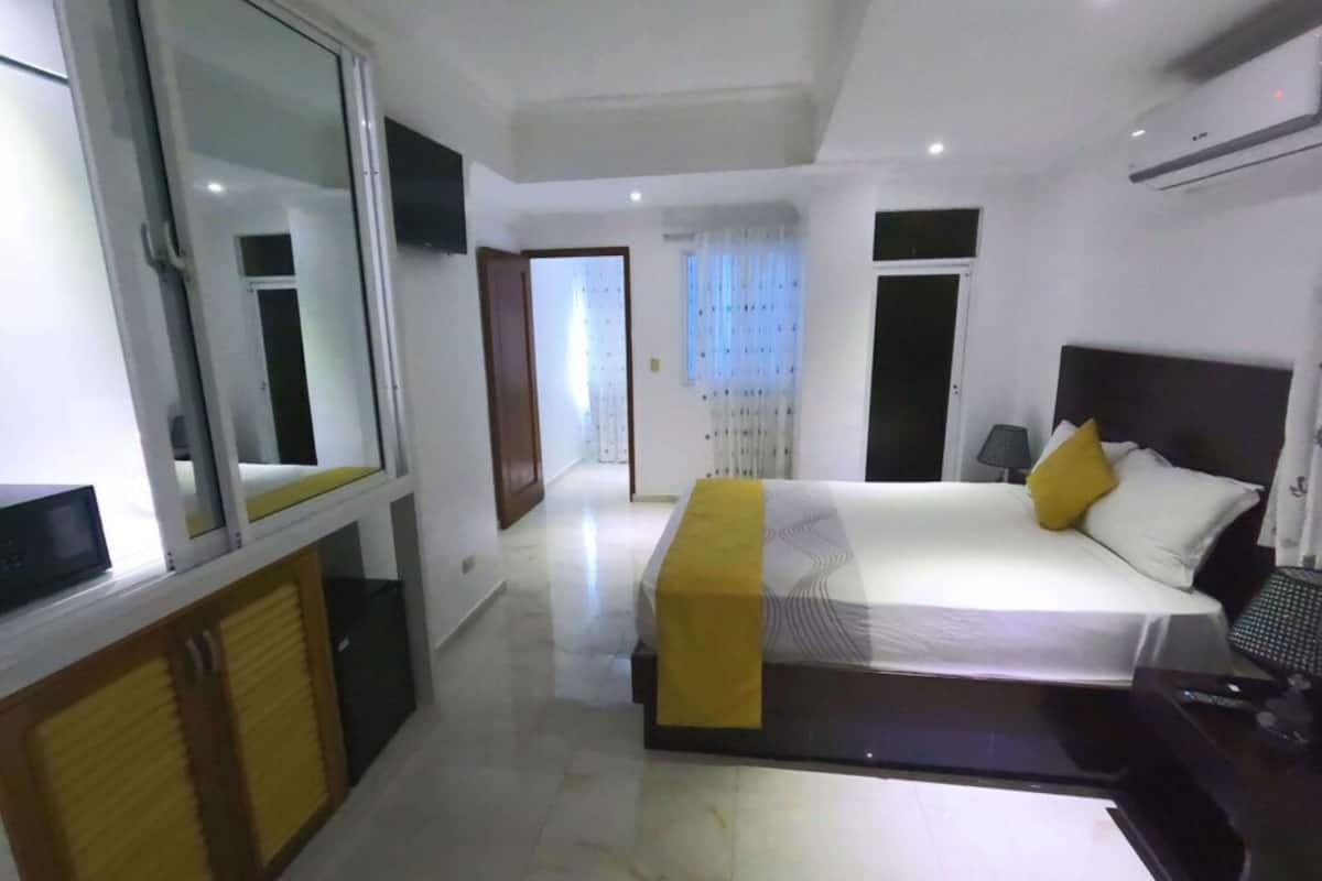 Een moderne hotelkamer met een groot bed, een nachtkastje, een spiegel en een kledingkast.