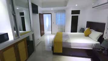 A modern hotel room with a large bed, a bedside table, a mirror, and a wardrobe.