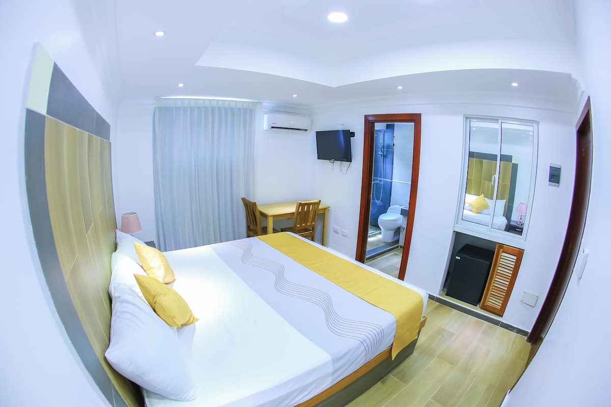 Een hotelkamer met een bed, een bureau, een stoel, een televisie en een badkamer.