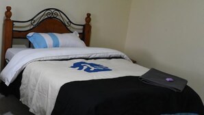 Un lit avec une tête de lit en bois, une literie blanche et une couverture bleue et noire.