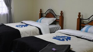 Deux lits avec des têtes de lit en bois et un rideau gris.
