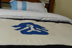 Un lit avec une literie blanche et bleue, un oreiller bleu et blanc, et une tête de lit blanche.