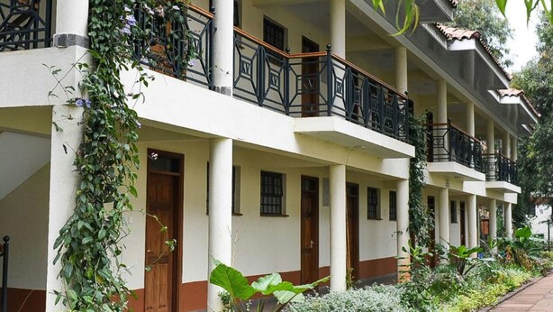 Un hôtel à plusieurs étages doté de balcons, d’une galerie couverte et d’une végétation luxuriante.