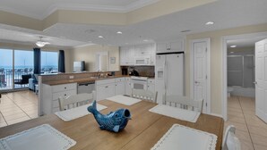 A spacious kitchen with white cabinets, a dining table with a fish-shaped centerpiece, and a view of the ocean through large windows.