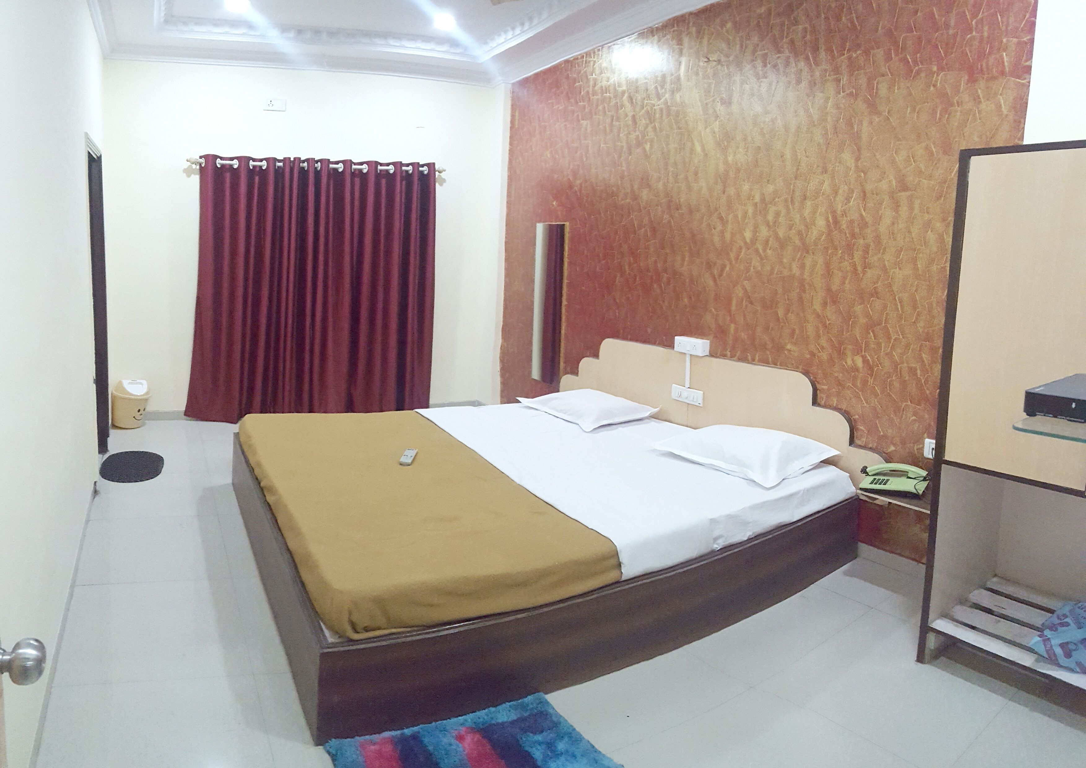 A neatly arranged bedroom with a bed, a bedside table, a telephone, and a wardrobe.