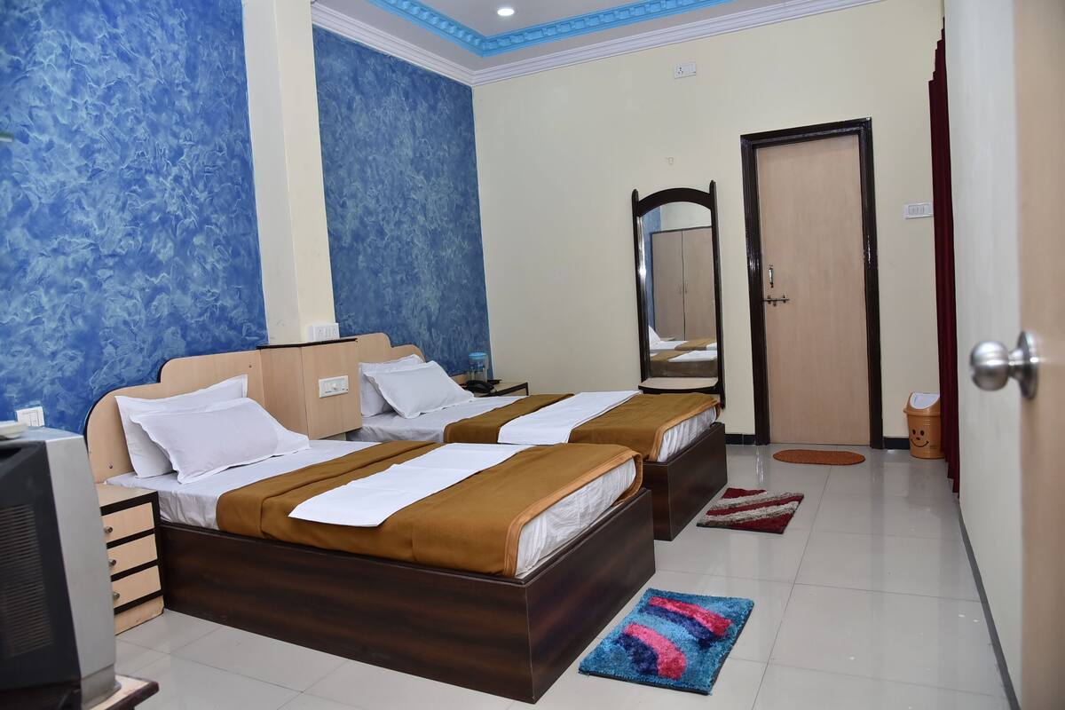 A hotel room with two beds, a television, a mirror, and a door.