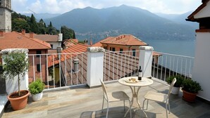 Un balcón con mesa y sillas con vistas a un lago y montañas.