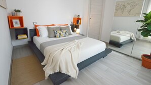 Un dormitorio moderno con cama, mesitas de noche, un espejo y una planta en maceta.