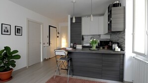 Una cocina moderna con una isla central, iluminación colgante y una planta en maceta.