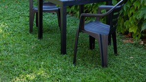 An outdoor patio with a table and chairs, surrounded by lush greenery and a fence. - LULLABY HOUSE LAZISE (Lazise)