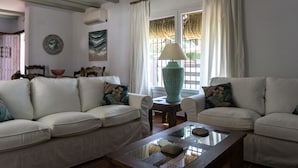 Una sala de estar con dos sofás blancos, una mesa de centro de cristal y una lámpara.