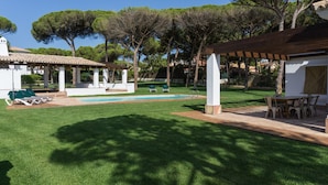 Un espacio exterior bien cuidado con piscina, sillas de descanso y una pérgola.
