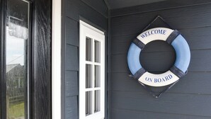 A dark gray door with a white window and a life ring with "WELCOME ON BOARD" text.