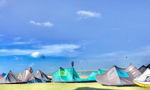 Una playa con varias tiendas de campaña y cielo despejado.