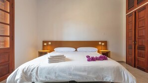 A neatly made bed with white linens, two bedside lamps, and a stack of white towels. - GC0285 Holiday house with shared pool in Mogán (Mogán)