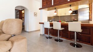 A modern kitchen with wooden cabinets, a stainless steel refrigerator, and a bar area with stools. - GC0285 Holiday house with shared pool in Mogán (Mogán)