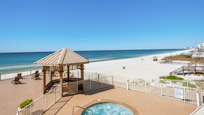 Een resort aan het strand met een houten prieel, een zwembad en uitzicht op het strand en de oceaan.