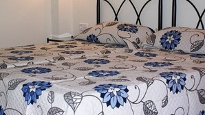 A bed with a floral-patterned bedspread, a black metal headboard, and a wall-mounted light fixture. - Lovely 2 bedrooms apartment in Torre Soli Nou (San Jaime Mediterráneo)
