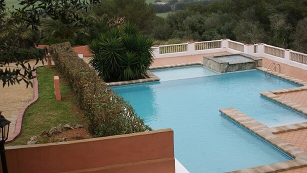 A rectangular pool with a stone border and a small waterfall feature. - Lovely 2 bedrooms apartment in Torre Soli Nou (San Jaime Mediterráneo)