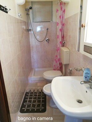 A bathroom with a shower, toilet, and sink.