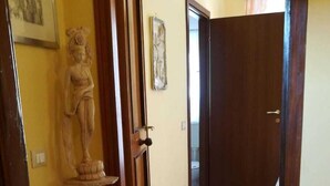 Un pasillo con una estatua, puertas de madera y piso de baldosas.
