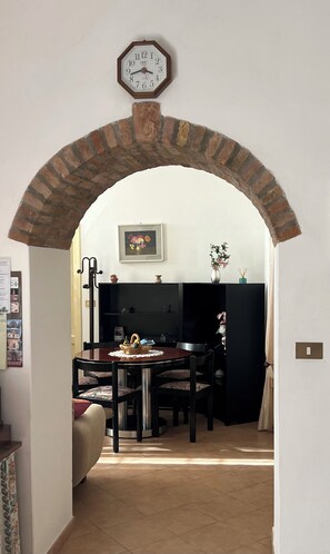 Un arco de entrada a un comedor con una mesa, sillas y un reloj encima.