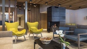 Un vestíbulo moderno con techo de madera, sillas amarillas, chimenea y sofá.