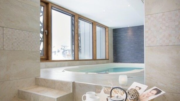 Un baño moderno con una bañera, una escalera y una mesa con tetera y tazas.