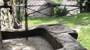 A rustic outdoor water feature with a stone basin and a hanging chain.