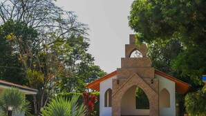 A small building with a stone facade, arched windows, and a tiled roof, surrounded by lush greenery. - Hotel Campestre Santa Lucia (Montenegro)