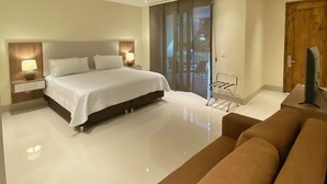 A modern bedroom with a large bed, bedside lamps, a sofa, and a sliding glass door leading to a balcony. - Hotel Campestre Santa Lucia (Montenegro)