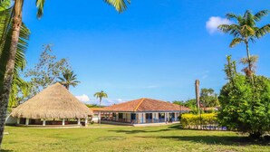 A resort with a thatched-roof hut, a covered building with a tiled roof, and lush greenery. - Hotel Campestre Santa Lucia (Montenegro)