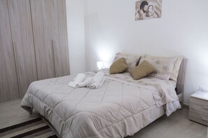 A neatly made bed with a beige duvet, two pillows, and rolled towels. - A stone's throw from downtown and the sea modern comfort and the scent of Marsala bread (Marsala)