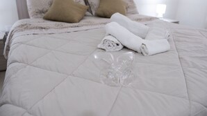 A neatly made bed with a quilted white duvet, two brown pillows, and a folded white towel on the bed. - A stone's throw from downtown and the sea modern comfort and the scent of Marsala bread (Marsala)