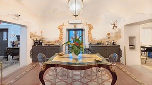 A dining area with a marble table, chairs, a vase with flowers, and a chandelier. - Moresco (Catania)