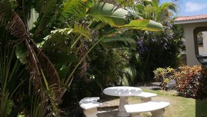 A garden with large banana plants, a white gazebo, and a well-maintained lawn. - Seabreeze Villa: Best rates. Charming, bright & spacious. Truly a home from home (Atlantic Shores)