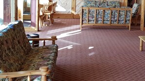 Una stanza accogliente con soffitto in legno, un divano decorato, un tavolo di legno e un'ampia finestra.