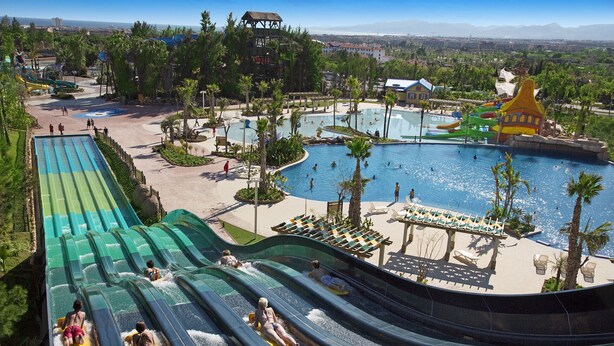 A water park with multiple water slides, a large pool, and surrounding greenery. - Alexis plus Zeus Salou  3121 (Salou)