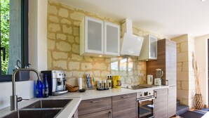 A modern kitchen with a stone backsplash, built-in appliances, and a large window. - Loire Valley with pool (Thizay)