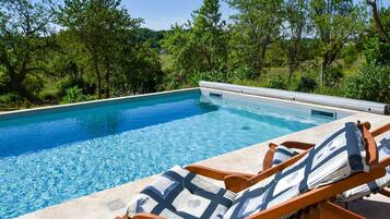 Een verwarmd zwembad en ligstoelen